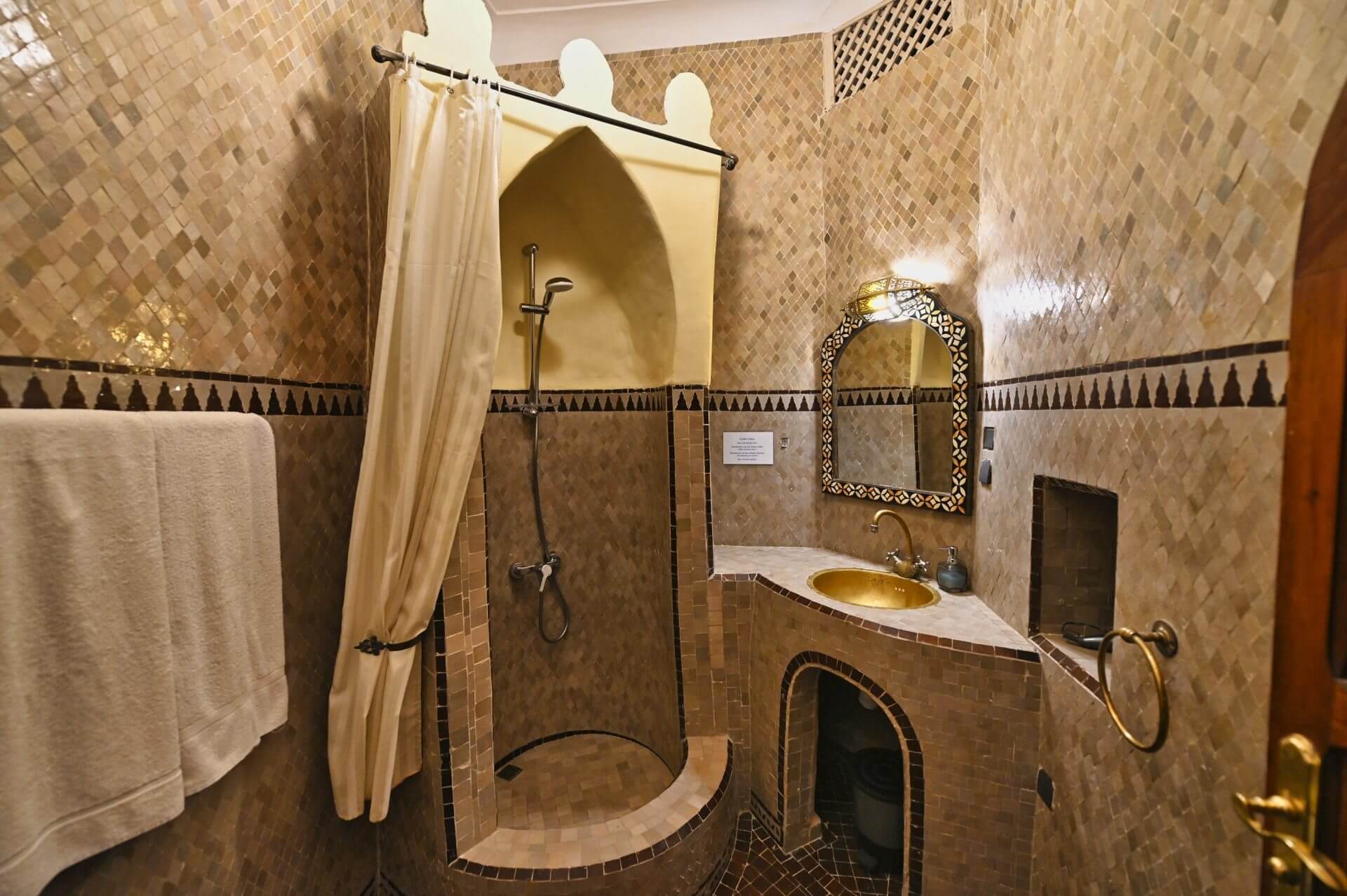 Badezimmer mit einer Dusche aus hellen Mosaikfliesen