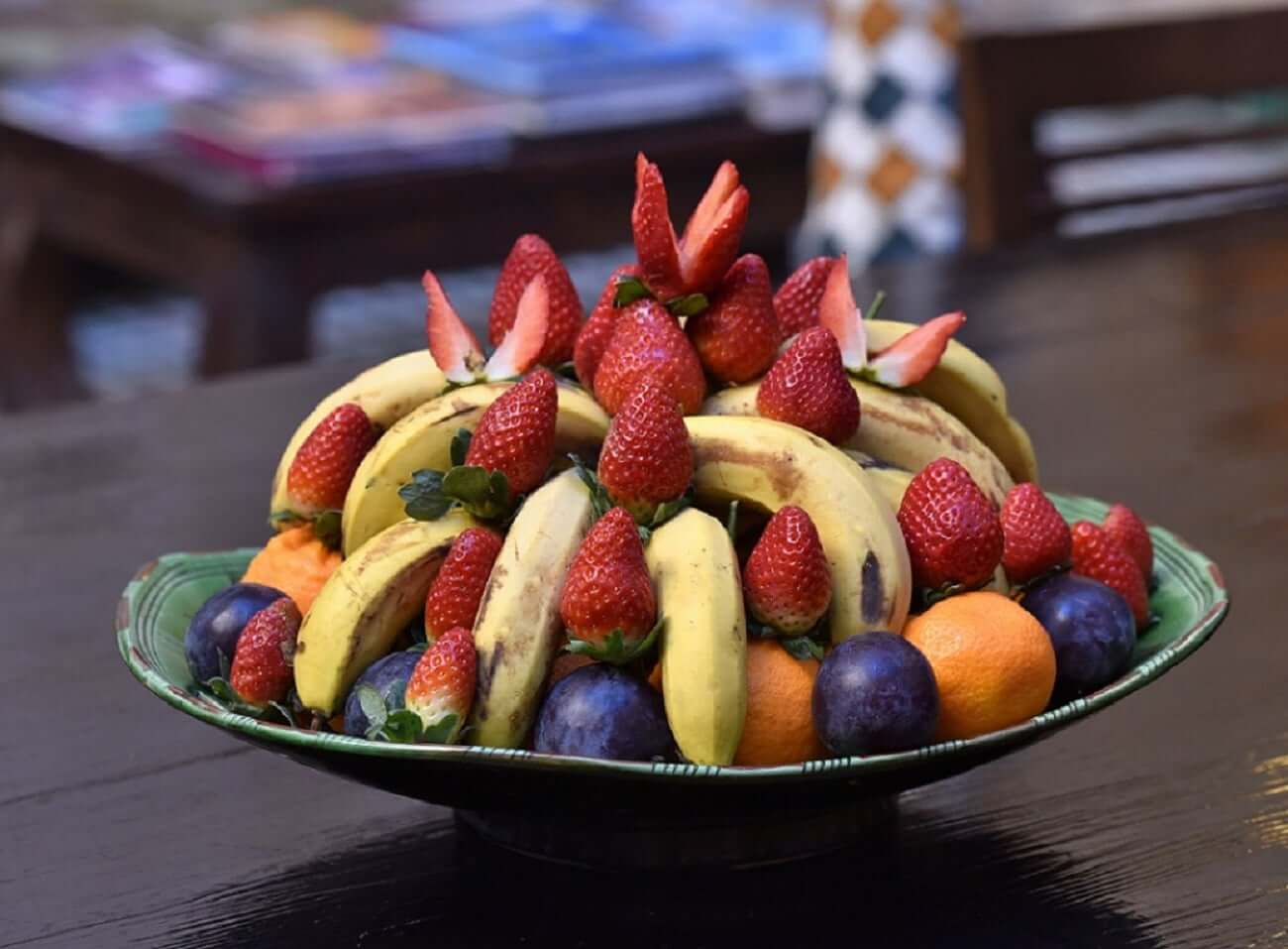 Obstteller mit Bananen, Orangen, Pflaumen und Erdbeeren