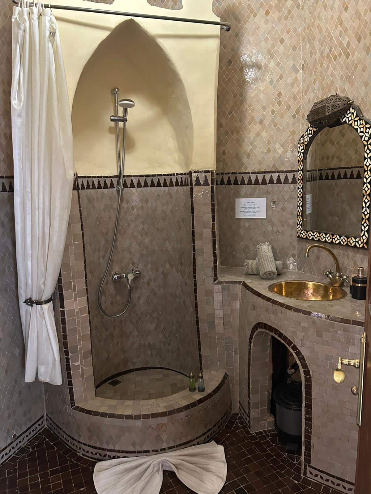 Badezimmer mit einer Dusche aus hellen Mosaikfliesen