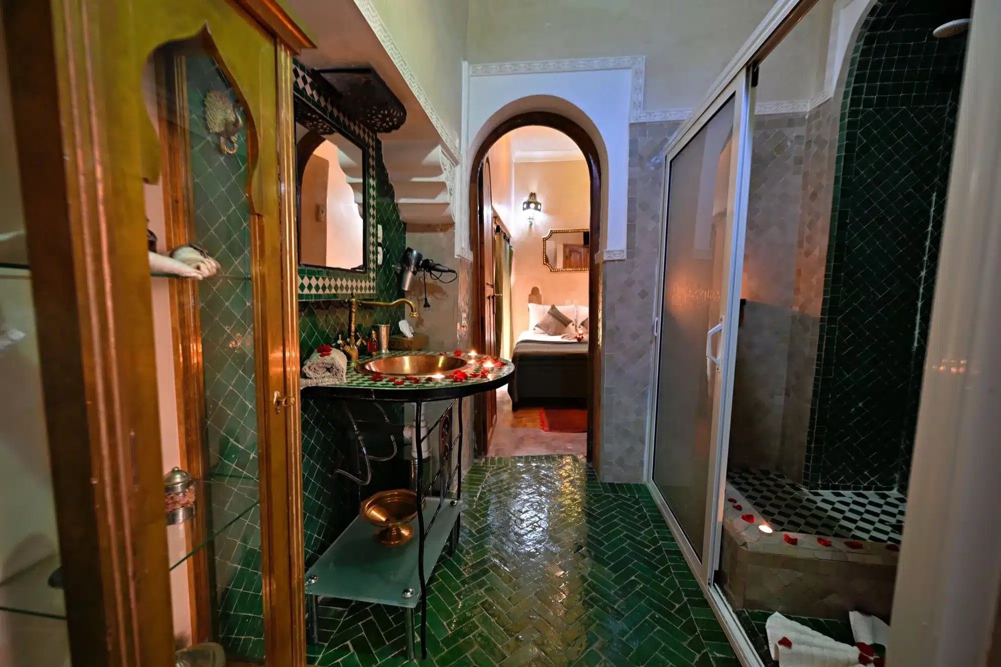 Marokkanisches Badezimmer im Riad mit grünen Mosaikfliesen (Zellige), einem kunstvollen Waschbecken aus Messing und Dusche.