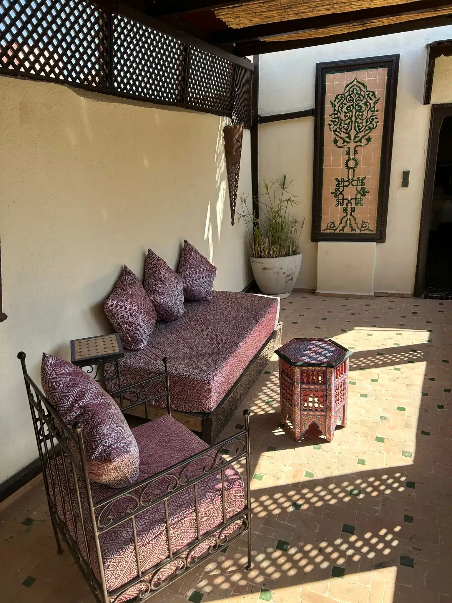 Sonnige Dachterrasse des Riads La Maison Nomade mit gemütlichen Sitzgelegenheiten und weitem Ausblick über die Medina von Marrakesch.