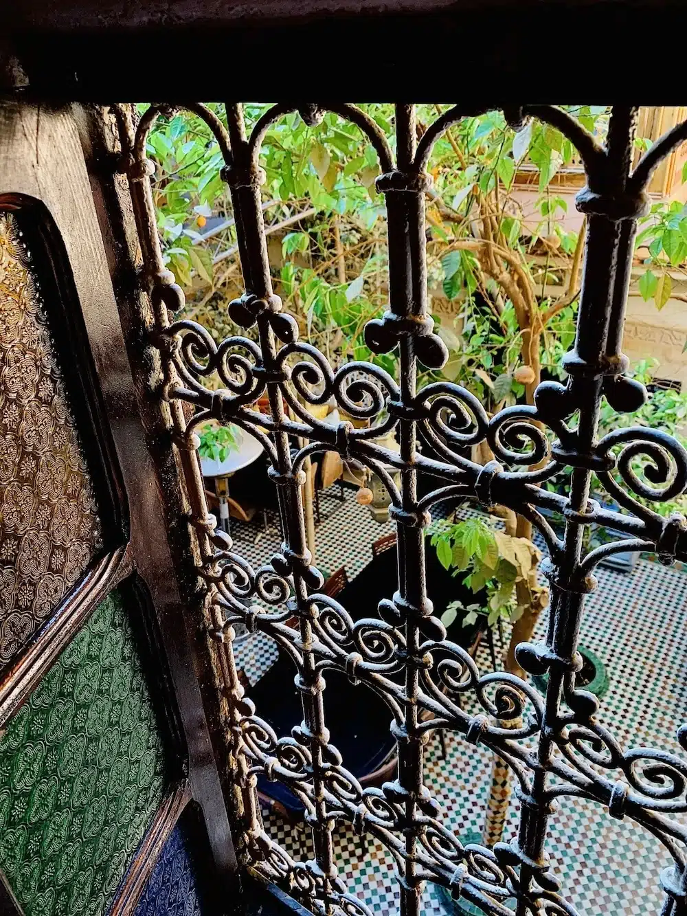 Blick aus dem Fenster des Zimmers Fortune durch kunstvolle Schmiedeeisen-Gitter in den ruhigen, begrünten Innenhof des Riads.